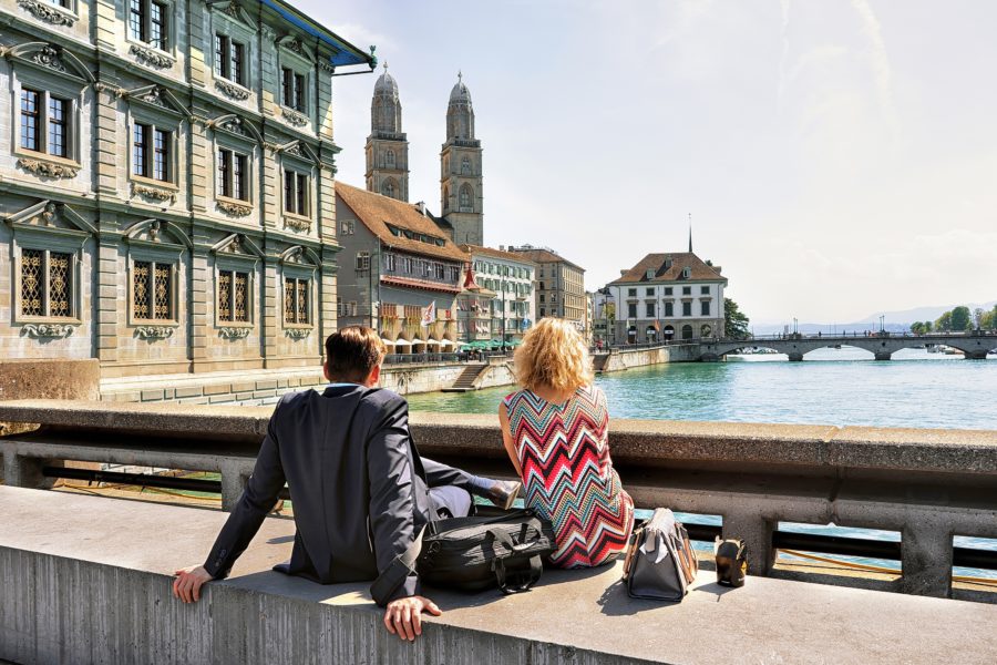 People sitting at Limmat River Quay and looking at Grossmunster